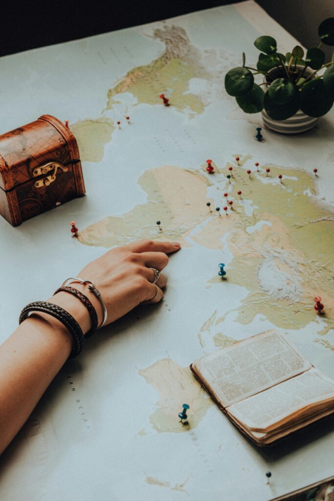 Hand pointing on a world map surrounded by travel essentials, sparking a sense of adventure.
