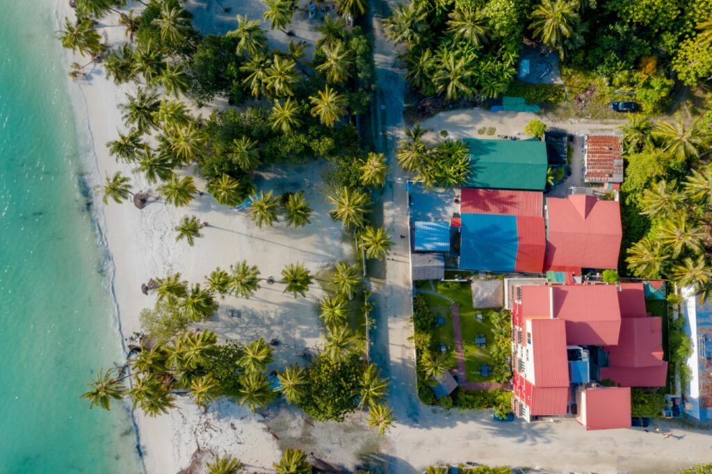 Aerial shot of a tropical beach with palm trees and colorful coastal homes. Perfect for travel ads.